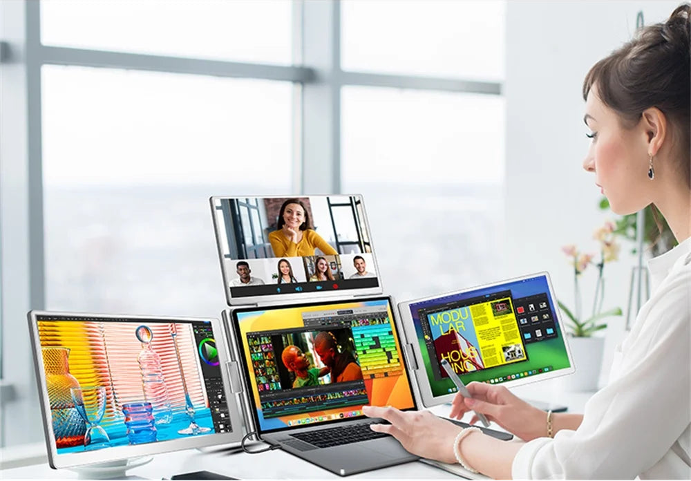 Person using a laptop with multiple displays for different tasks in an office setting.